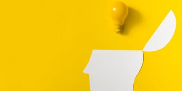 yellow light bulb open paper cut out head against colored background 23 2147890090