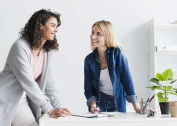 friendly female colleagues discussing work laughing office 23 2148180676