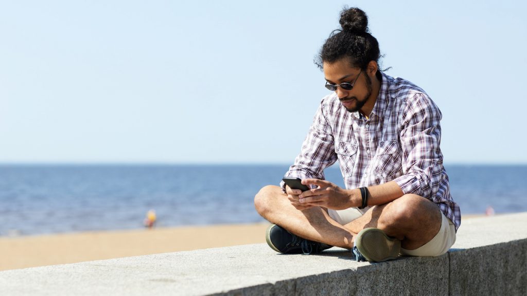Persona en la playa y revisando sus redes sociales 
