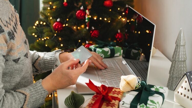 Female hand holding card and using laptop for Christmas online shopping. Holiday online shopping concept. Winter holidays sales, Black Friday