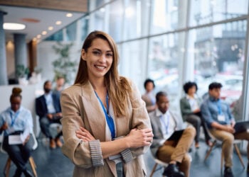 Happy businesswoman with arms crossed in board room during a seminar looking at camera.