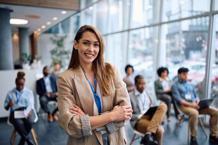 Happy businesswoman with arms crossed in board room during a seminar looking at camera.