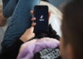 Nizhny Novgorod, Russia October 03 2020: child with phone in his hands is lying at home on bed. Social Media tiktok is loaded on screen.