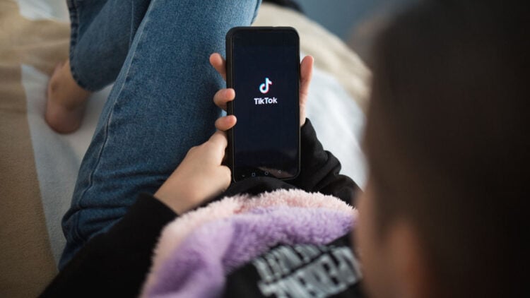 TikTok prepara una función para realizar transferencias de dinero mediante su plataforma 1 Nizhny Novgorod, Russia October 03 2020: child with phone in his hands is lying at home on bed. Social Media tiktok is loaded on screen.